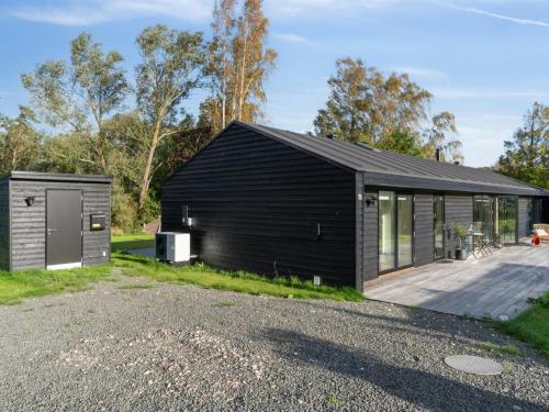 una casa negra con garaje y entrada en Holiday Home Tessa - 1-6km from the sea in Sealand by Interhome en Græsted