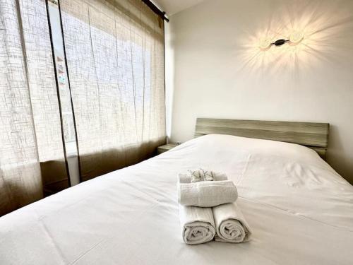 two towels on a white bed with a window at Stade de France 12min - Idéal JO 2024 in Saint-Denis