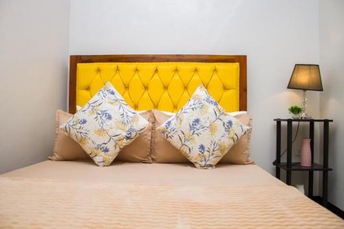a bedroom with a bed with a yellow headboard and pillows at RB Modern Condos in Zamboanga