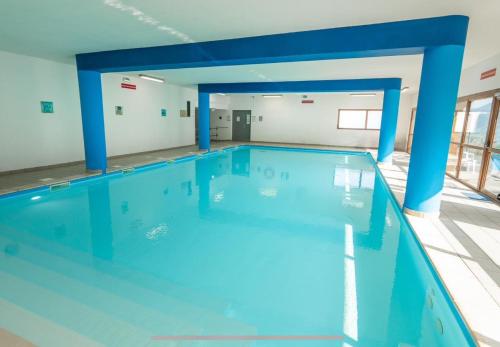 una gran piscina con columnas azules en un edificio en Centre Orres 1800 - 4/6 pers. Rénové - Parking, en Les Orres
