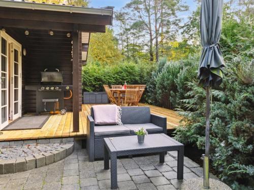 a patio with a couch and a table and an umbrella at Holiday Home Eddi - 10km from the sea in Djursland and Mols by Interhome in Rønde