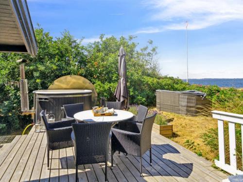 um deque com uma mesa, cadeiras e um guarda-sol em Holiday Home Asmine - 30m from the sea in Funen by Interhome em Millinge