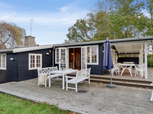 a black cottage with a table and chairs on a deck at Holiday Home Rami - 2km from the sea in Sealand by Interhome in Tisvildeleje