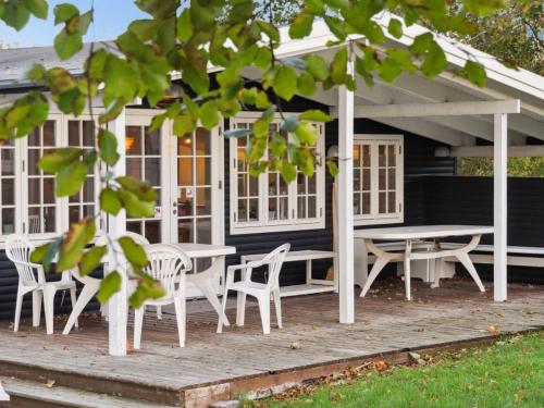 uma mesa de piquenique e cadeiras num alpendre de uma casa em Holiday Home Rami - 2km from the sea in Sealand by Interhome em Tisvildeleje