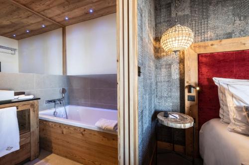 a bathroom with a bath tub next to a bed at Chalet Carte Blanche Golden Jubilée in Val Thorens