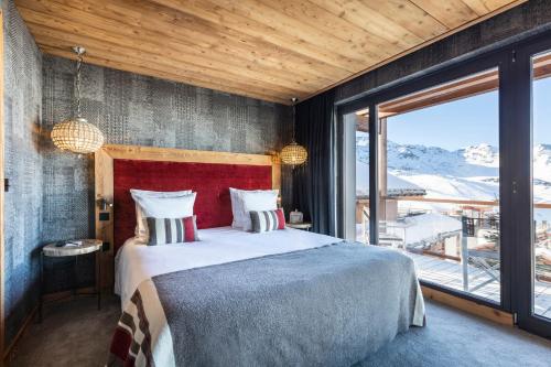 a bedroom with a large bed and a large window at Chalet Carte Blanche Golden Jubilée in Val Thorens