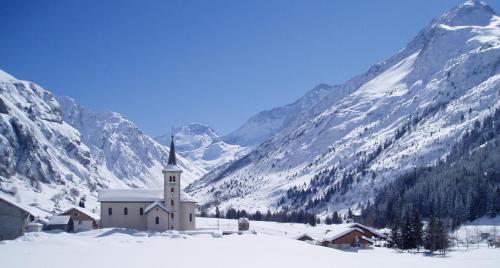 a church in the snow with mountains in the background at Chalet Alpin Luxe, Jacuzzi, Vue in Champagny-en-Vanoise