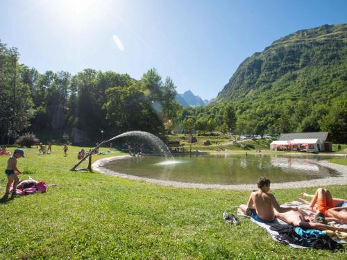 Un groupe de personnes se posant dans l'herbe près d'un étang dans l'établissement Apartment Les Hameaux de la Perrière-2 by Interhome, à Saint-Colomban-des-Villards