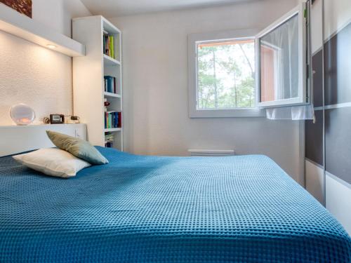 une chambre avec un lit bleu avec une fenêtre dans l'établissement Holiday Home Les Landaises-12 by Interhome, à Lacanau