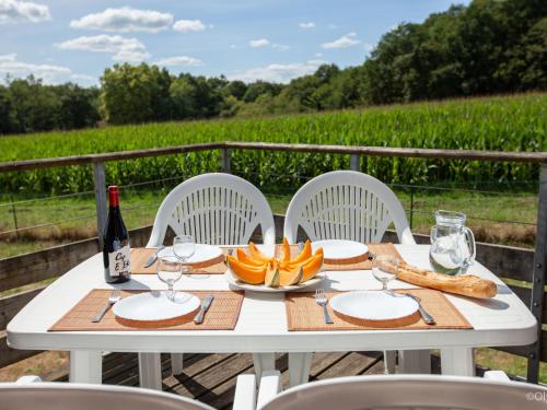 - une table blanche avec une bouteille de vin et du pain dans l'établissement Apartment Les Hameaux de La Chalosse-1 by Interhome, à Cassen
