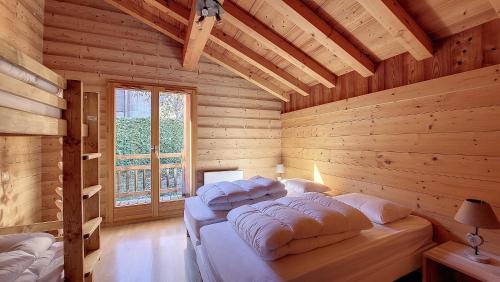 Un dormitorio con dos camas en una cabaña de madera. en Chalet MB, en Saint-Jean-dʼAulps