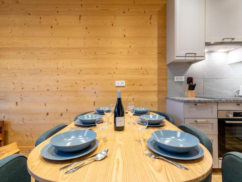- une table en bois avec des assiettes et une bouteille de vin dans l'établissement Apartment Le Hameau du Borsat - Val Claret-14 by Interhome, à Tignes