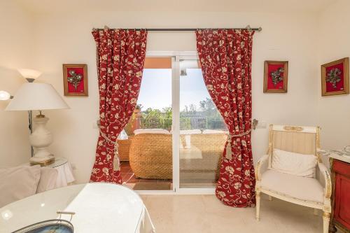 Cette chambre dispose de rideaux rouges, d'une table et d'une chaise. dans l'établissement Spikes, à Guadiaro