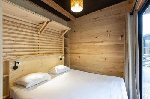 a bedroom with wooden walls and a bed with two pillows at CityKamp Colmar in Horbourg