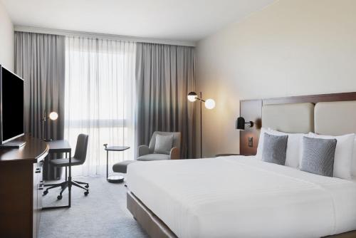 Habitación de hotel con cama grande y escritorio. en Courtyard by Marriott Basel en Pratteln