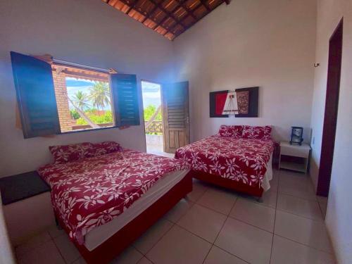 a bedroom with two beds and a window at Casa de Praia Em Aguas Belas 3 suites in Cascavel