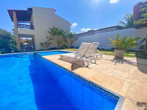 a pair of chairs sitting next to a swimming pool at Casa de Praia Em Aguas Belas 3 suites in Cascavel