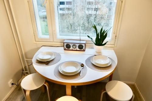 una pequeña mesa blanca con sillas y una ventana en Havi Apartment, en Riihimäki