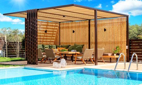 a pavilion with a table and chairs next to a pool at Cretan Sunrise Villa Heated Pool in Dhimitroulianá