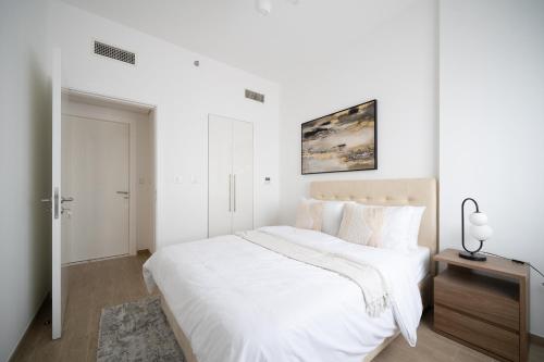 a white bedroom with a large bed with white sheets at ALH Vacay - The Nook 1 - 2 Bedrooms - Near Metro in Dubai