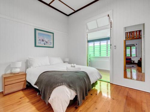 a white bedroom with a large bed and a window at Historic Character-filled Jade Cottage in Coalfalls