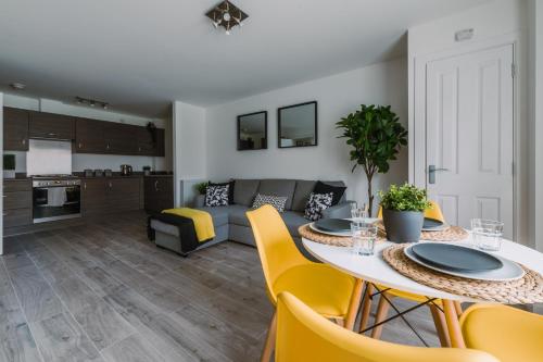a kitchen and living room with a table and yellow chairs at SleepWell Apartments in Glasgow