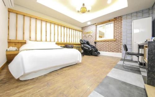 a bedroom with a large white bed and two chairs at Cheonan Business Hotel in Cheonan
