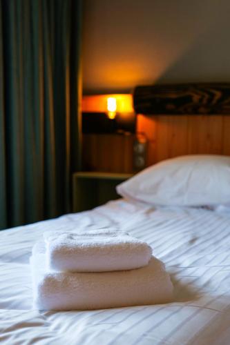 two towels sitting on top of a bed at Le Motel du Gaschney in Muhlbach-sur-Munster
