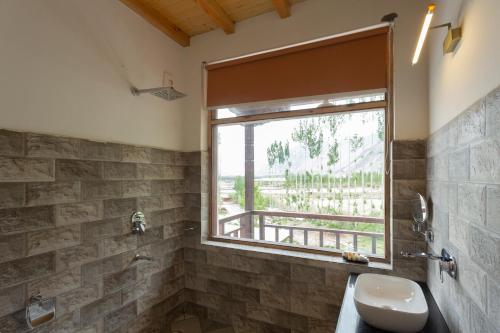 a bathroom with a window and a toilet and a sink at Sand Dunes Retreat in Leh