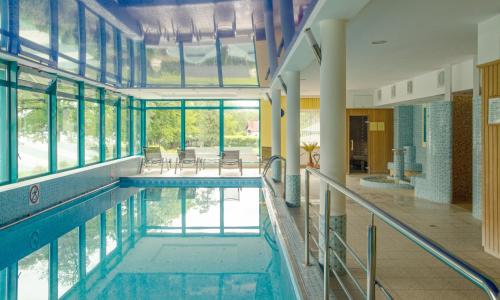 a pool in a building with windows and a swimming pool at SPA Barlinek, Hotel Alma & SPA in Barlinek