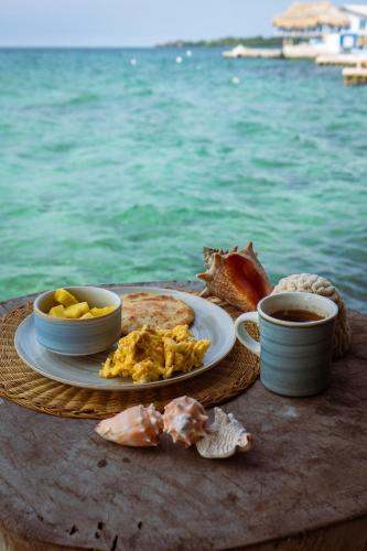 a plate of food on a table next to the water at Hostel Santa Cruz del Islote in Santa Cruz del Islote