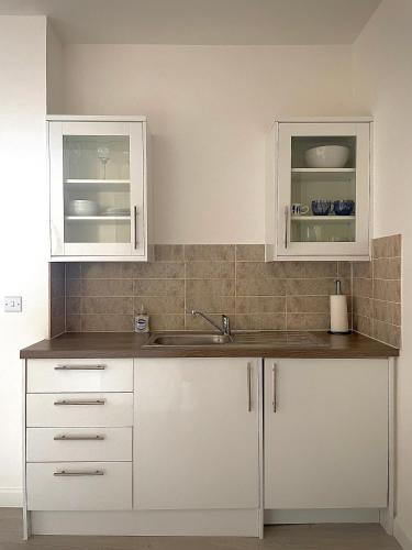 a kitchen with white cabinets and a sink at Central 2-bedroom apartment, Montrose in Montrose