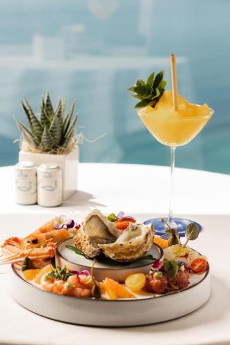a plate of food on a table with a drink at San Domenico Palace, Taormina, A Four Seasons Hotel in Taormina