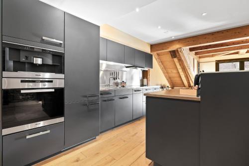 a kitchen with gray cabinets and stainless steel appliances at A&Y Oldtown Penthouse Loft Luzern in Luzern