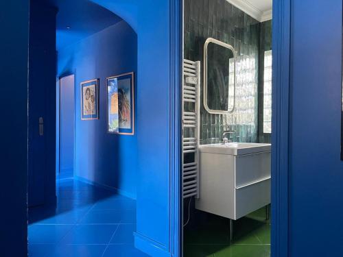 a blue bathroom with a sink and a mirror at Luxury Jardin Majorelle paris orly avec jacuzzi in Vigneux-sur-Seine