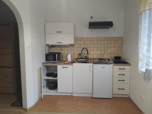 a small kitchen with white cabinets and a sink at Jaskółka in Lądek-Zdrój