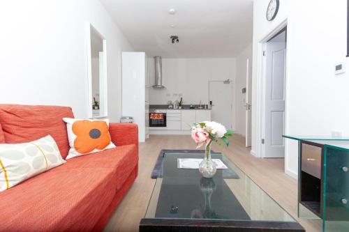 a living room with a red couch and a vase of flowers at One Bedroom apartment Serviced apartment Smethwick flat 319 in Birmingham