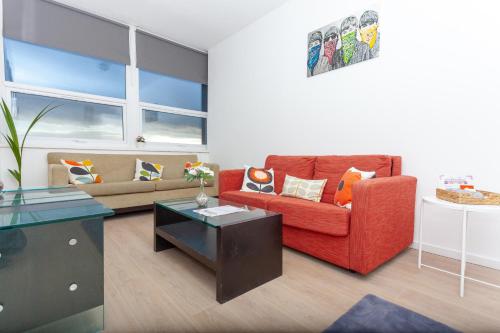 a living room with a red couch and a table at One Bedroom apartment Serviced apartment Smethwick flat 319 in Birmingham