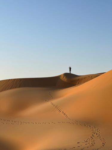 a man standing on a sand dune in the desert at Liwa Nights ليالي ليوا in Liwa