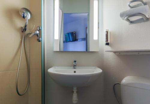 a bathroom with a sink and a shower with a mirror at B&B HOTEL Nancy Laxou Zenith in Nancy