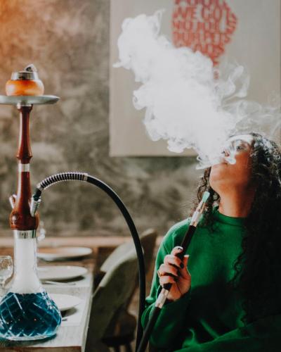 a woman is blowing smoke on a pipe at 7 Rooms Hotel in Tserovani