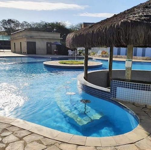 a swimming pool with a thatched roof at Apt B215 Quartier - Aldeia das Águas in Barra do Piraí