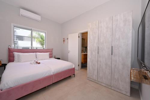a bedroom with a pink bed and a tv at הבית בלב כנען - וילה מהממת עם בריכה פרטית מחוממת בצפת in Safed
