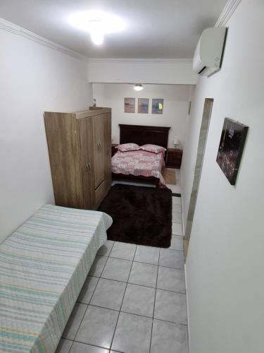 a bedroom with two beds and a tv in it at Kitnets em Caraguatatuba in Caraguatatuba