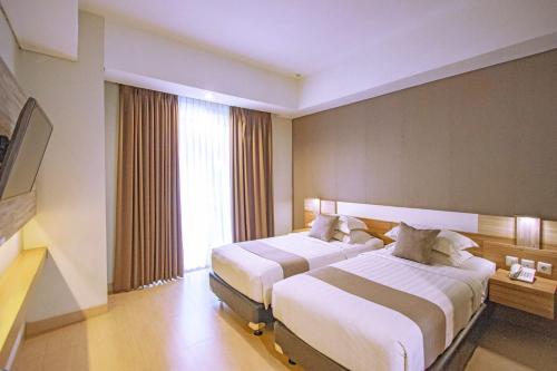a hotel room with two beds and a window at Hotel FortunaGrande Seturan Yogyakarta in Yogyakarta