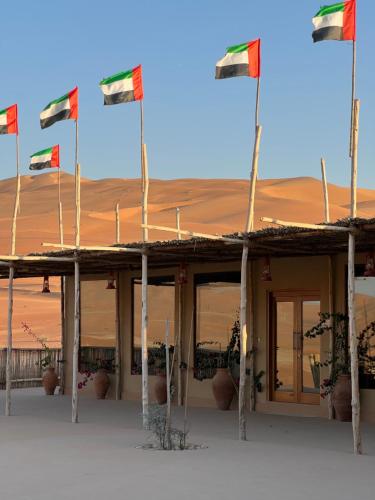a building with several flags in the desert at Liwa Nights ليالي ليوا in Liwa