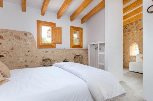 a white bed in a room with wooden ceilings at Cal Tio 1 Agroturismo YourHouse in Costitx