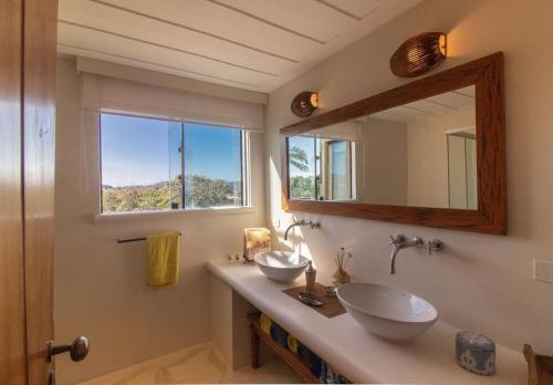 a bathroom with two sinks and a mirror at Mansão Imponente com Seis Suítes a 1min das Areias Praia da Ferradura Por Luxury Rentals in Búzios