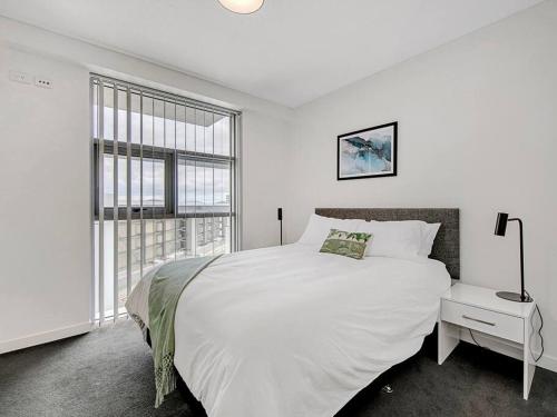 a white bedroom with a large bed and a window at Spectacular River View Apartment in Brisbane
