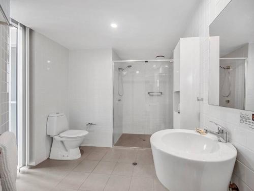 a white bathroom with a toilet and a sink at Spectacular River View Apartment in Brisbane